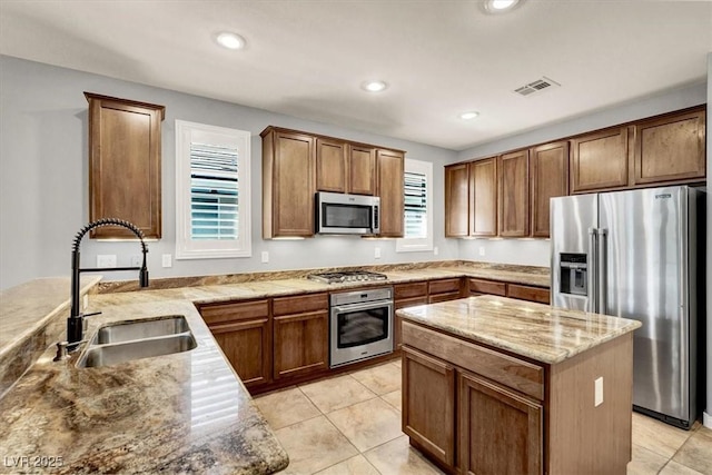 kitchen with appliances with stainless steel finishes, a sink, light stone countertops, recessed lighting, and light tile patterned floors