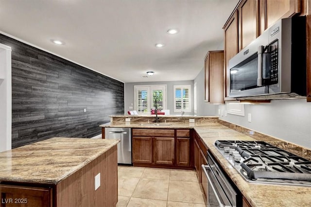 7806 Sundial Peak St, Las Vegas, NV 89166 - kitchen featuring stainless steel appliances, a sink, an accent wall, a peninsula, and brown cabinets