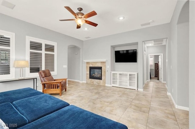 7806 Sundial Peak St, Las Vegas, NV 89166 - living area with arched walkways, a ceiling fan, a tile fireplace, baseboards, and recessed lighting