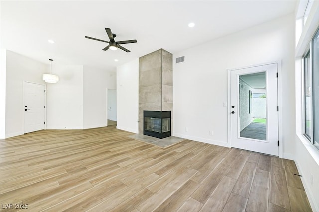 unfurnished living room featuring a fireplace, light wood-type flooring, a ceiling fan, visible vents, and recessed lighting