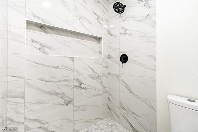full bathroom featuring a tile shower and toilet