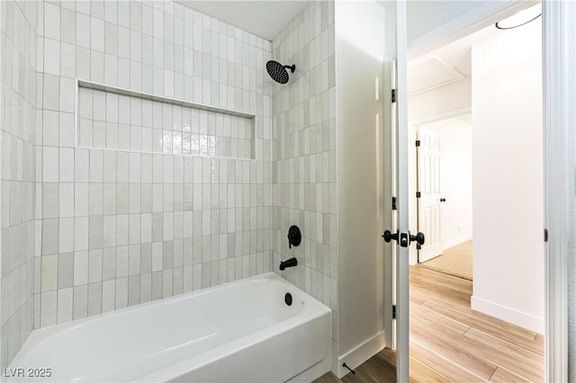 bathroom with baseboards, wood finished floors, and shower / tub combination