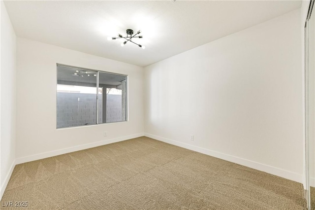 spare room featuring light colored carpet and baseboards