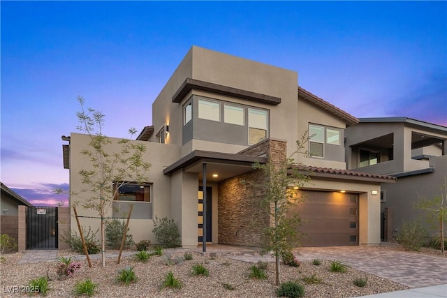 contemporary home with a garage, stucco siding, and a gate