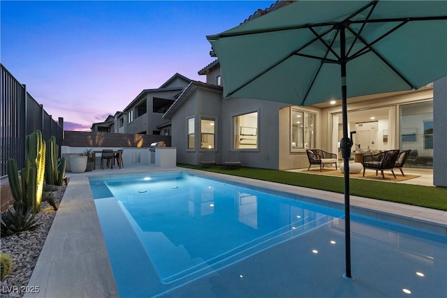pool at dusk with fence, a fenced in pool, a patio, and exterior kitchen