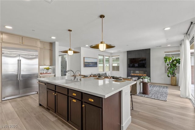 kitchen with open floor plan, light wood-type flooring, a sink, and appliances with stainless steel finishes