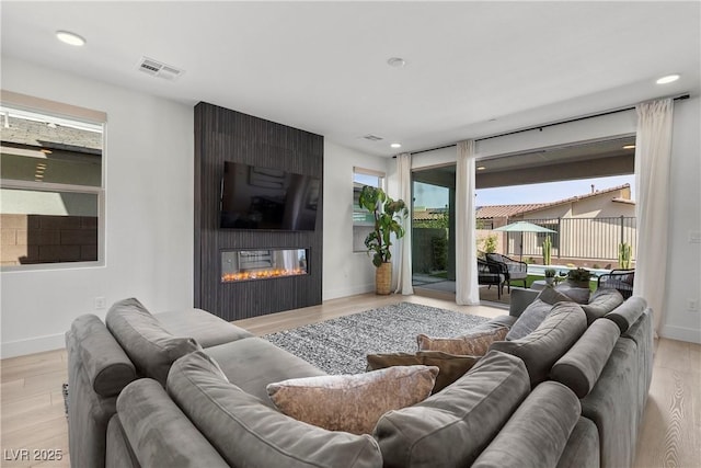 living area featuring light wood-style floors, visible vents, and baseboards