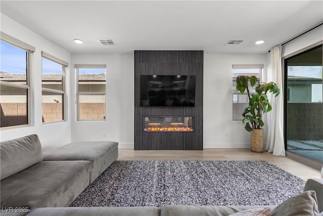 living room with visible vents, recessed lighting, wood finished floors, and a fireplace