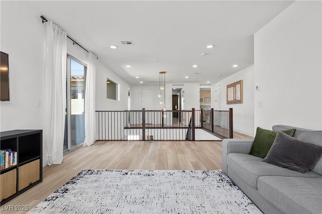 living room featuring light wood-style flooring, visible vents, and recessed lighting