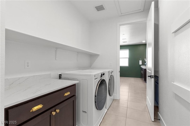 clothes washing area featuring light tile patterned floors, visible vents, baseboards, cabinet space, and washing machine and clothes dryer