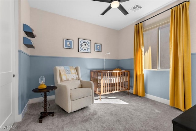 bedroom with visible vents, baseboards, a nursery area, ceiling fan, and carpet floors