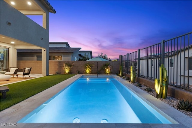 pool at dusk featuring a fenced backyard, a fenced in pool, and a lawn