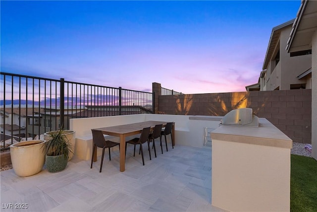 view of patio / terrace with exterior kitchen, outdoor dining area, a fenced backyard, and a grill