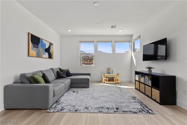 living area with visible vents, baseboards, and wood finished floors