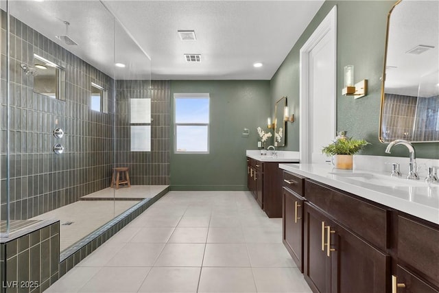 bathroom with a sink, visible vents, tile patterned floors, and walk in shower