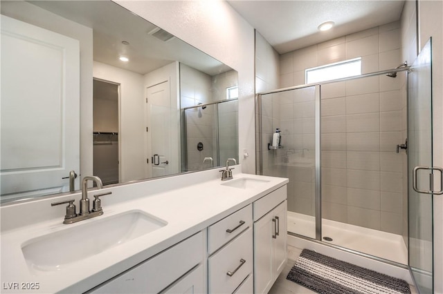 full bathroom featuring double vanity, a sink, and a shower stall