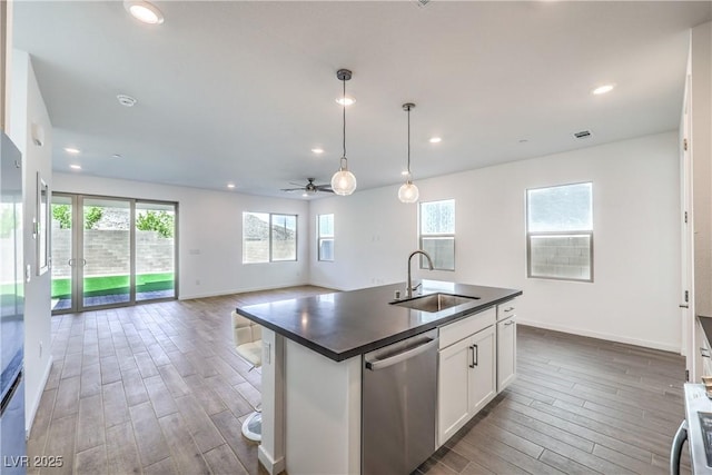 kitchen with wood finished floors, dark countertops, ceiling fan, a sink, and dishwasher