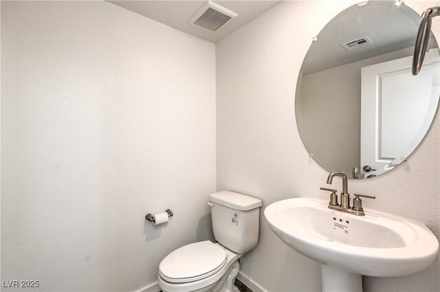 half bathroom featuring baseboards, visible vents, and a sink