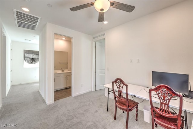 office space with a sink, ceiling fan, light colored carpet, and visible vents