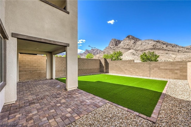 view of yard with a patio, a mountain view, and a fenced backyard