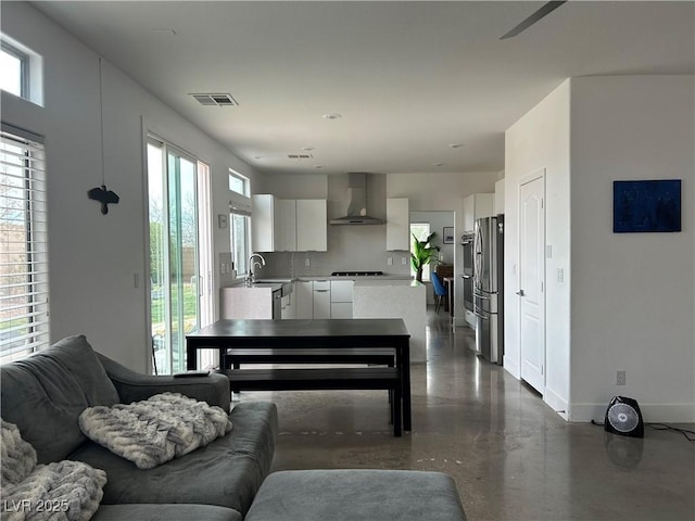 living area featuring a wealth of natural light, visible vents, baseboards, and concrete flooring