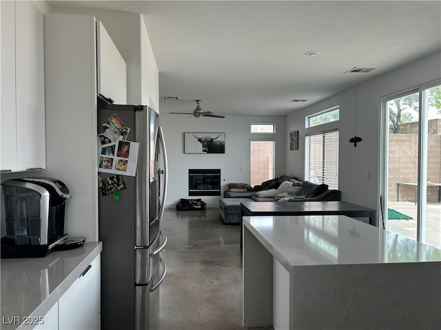 kitchen featuring white cabinets, stainless steel fridge, open floor plan, ceiling fan, and finished concrete floors