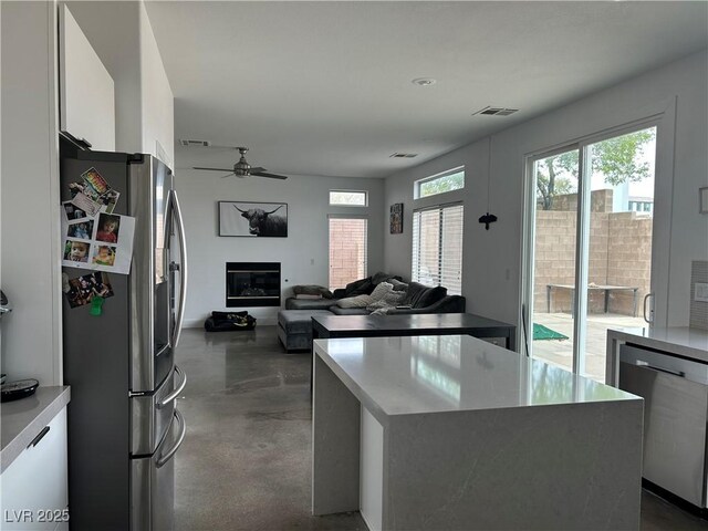 kitchen with modern cabinets, concrete flooring, a ceiling fan, white cabinets, and appliances with stainless steel finishes