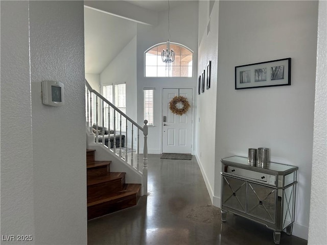 entryway with concrete floors, baseboards, a high ceiling, a textured wall, and stairs