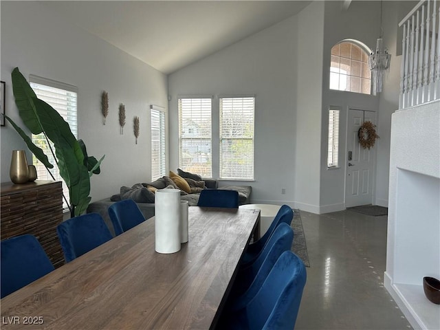 dining space with finished concrete floors, high vaulted ceiling, baseboards, and a wealth of natural light