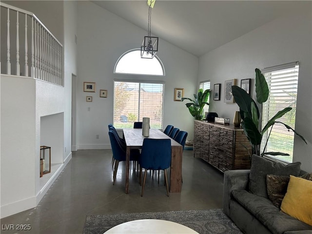 dining room with high vaulted ceiling, finished concrete floors, and baseboards