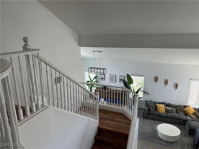 stairway featuring a chandelier and wood finished floors