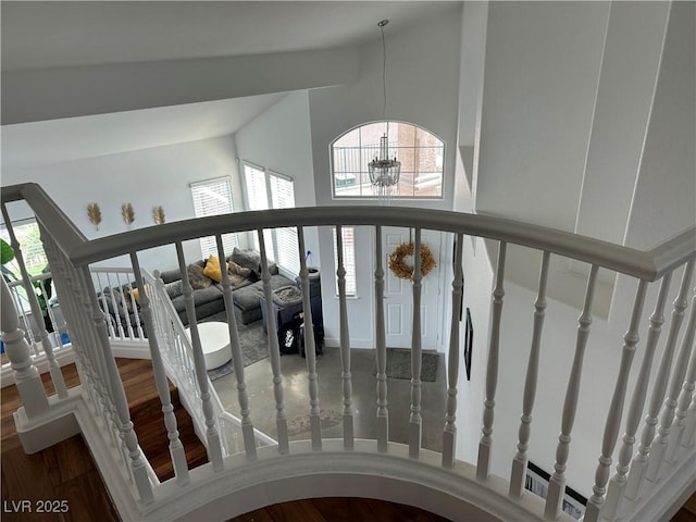 staircase with visible vents, high vaulted ceiling, an inviting chandelier, and wood finished floors