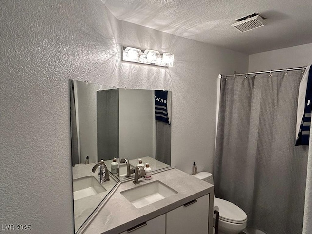 full bath featuring vanity, a textured wall, a textured ceiling, toilet, and visible vents