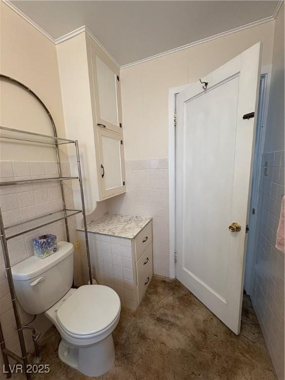 bathroom with toilet, tile walls, and wainscoting