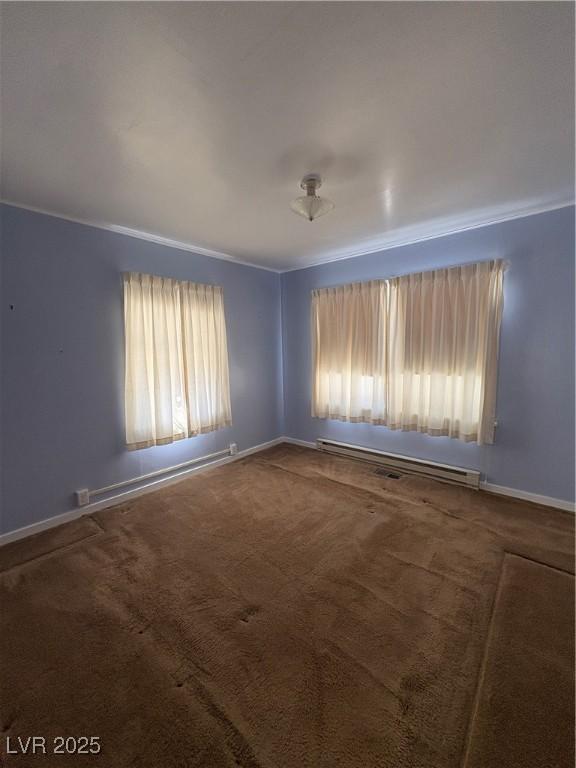 carpeted spare room featuring a baseboard heating unit, baseboards, and ornamental molding