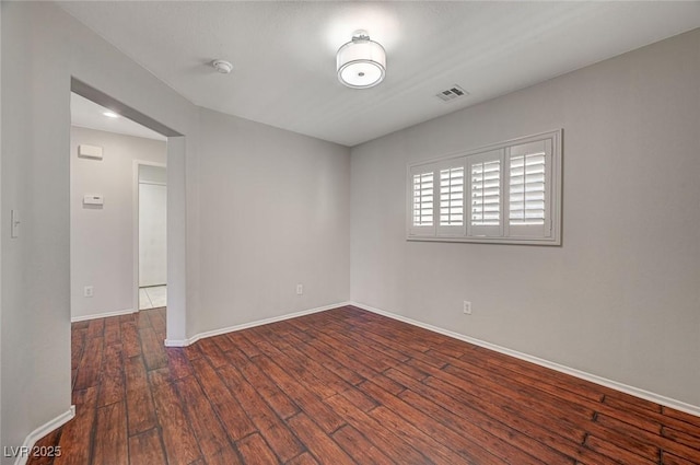 unfurnished room with visible vents, baseboards, and hardwood / wood-style flooring