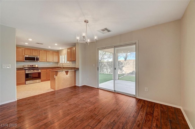 kitchen featuring stainless steel appliances, a notable chandelier, baseboards, and wood finished floors