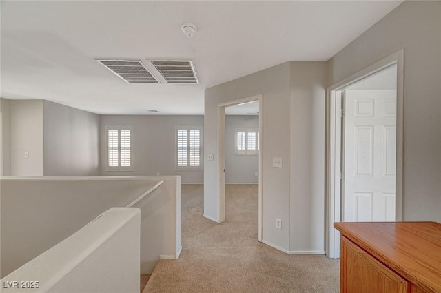 corridor with light carpet, an upstairs landing, baseboards, and visible vents