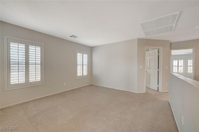 empty room featuring visible vents, a wealth of natural light, and light carpet