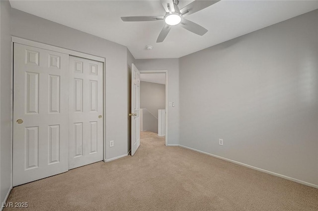 unfurnished bedroom featuring a closet, baseboards, a ceiling fan, and light carpet