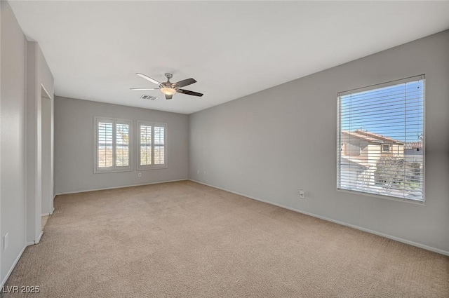 spare room featuring light carpet, visible vents, and a ceiling fan