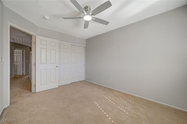 unfurnished bedroom featuring a closet, light colored carpet, baseboards, and a ceiling fan