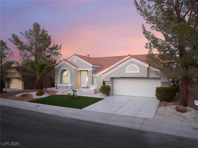 view of front of home featuring driveway, stucco siding, an attached garage, and a tile roof