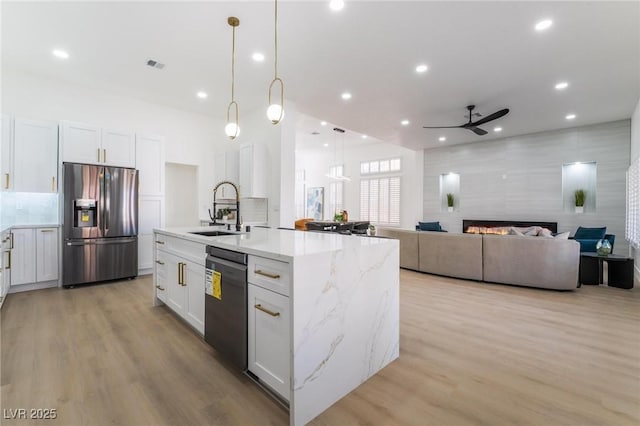 kitchen featuring white cabinets, stainless steel fridge, black dishwasher, a sink, and ceiling fan