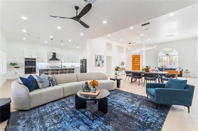 living area with recessed lighting, a ceiling fan, and light wood-style floors