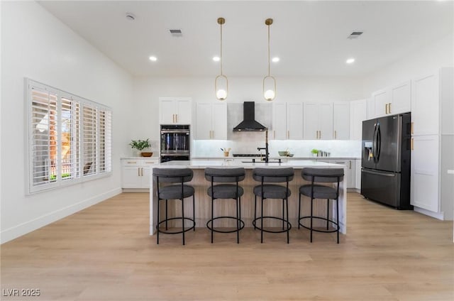 kitchen featuring white cabinets, black refrigerator with ice dispenser, visible vents, and wall chimney exhaust hood