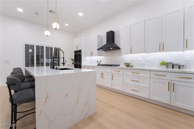 kitchen with a kitchen breakfast bar, wall chimney range hood, black appliances, a sink, and backsplash