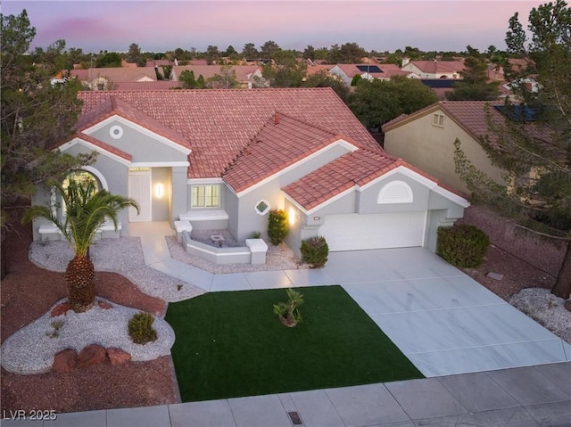 mediterranean / spanish-style home featuring stucco siding, driveway, a tile roof, a garage, and a yard