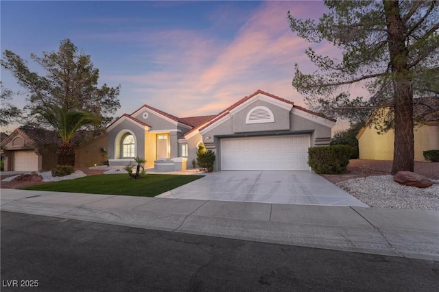 mediterranean / spanish home with an attached garage, concrete driveway, stucco siding, and a tile roof