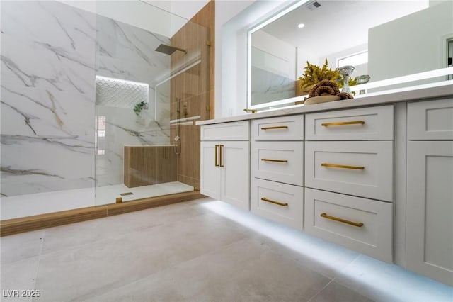 full bathroom featuring a marble finish shower, tile patterned floors, and double vanity